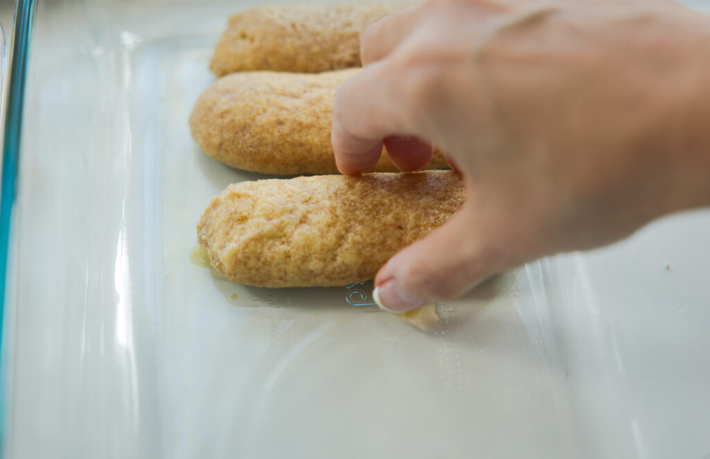 placing soaked ladyfingers in the casserole dish